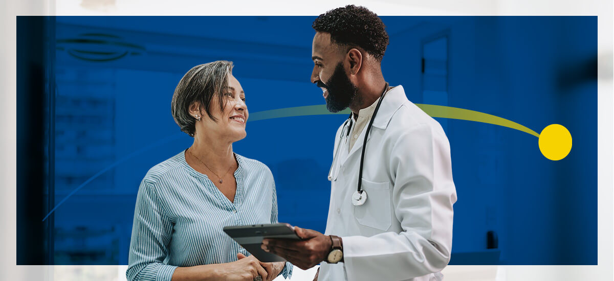 A male doctor holds a tablet while speaking to his patient